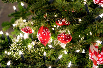 Close up of an illuminated Christmas tree with red and white decoration such as baubles, candy canes and mushrooms.
