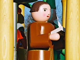 shaped, painted wooden figure with brown robe and an open book