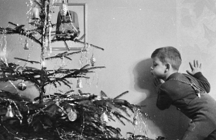 Frank Palmowski: Die Kerzen werden ausgeblasen, Erfurt, 1966 Schwarz-weiß Foto eines Kindes, das die Kerzen einen Weihnachtsbaumes auspustet