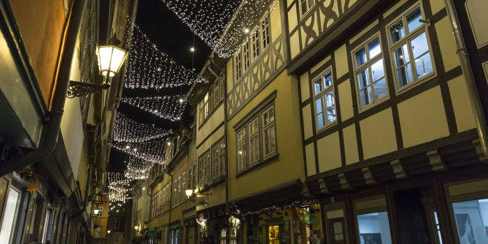 Foto: Weihnachtsbeleuchtung über der Krämerbrücke © Stadtverwaltung Erfurt Abendliches Foto einer Brücke mit rechts und links Häusern, zwischen den Häusern hängen Lichterketten