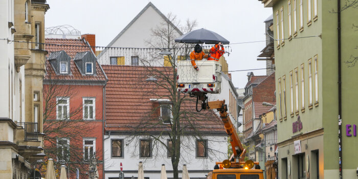 An der Rathausbrücke in Erfurt hängen Mitarbeiter des Straßenbetriebshofes Weihnachtsbeleuchtung auf. 