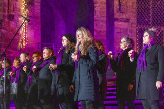 ein Chor auf den Stufen des Erfurter Doms, die Frauen halten Teelichter in der Hand