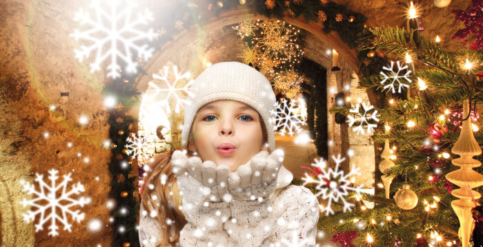 Mädchen pustet Schneekristalle aus dem festlich weihnachtlichen Gewölbe