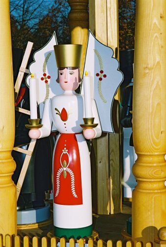 gedrechselte, bemalte Holzfigur mit weißem Gewand, Flügeln, Hut und Kerzen in der Hand