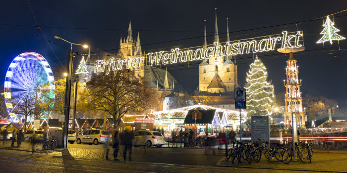 The focus is on the illuminated lettering Erfurt Christmas Market. In the background are the cathedral and some attractions as the big wheel and the Christmas pyramid.