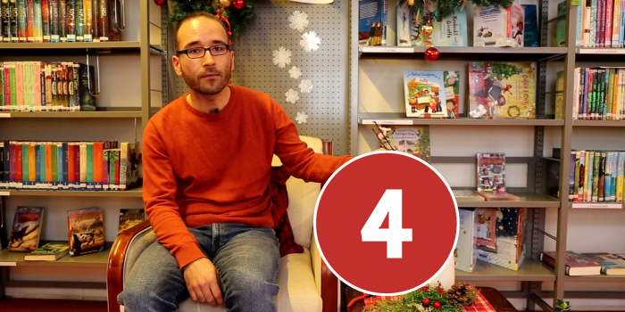 Männliche Person sitzt auf einem Sessel in einem Raum mit Bücherregalen