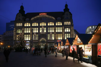 Visitors stand in front of Christmas stalls on the Anger with a Christmas evening mood. 